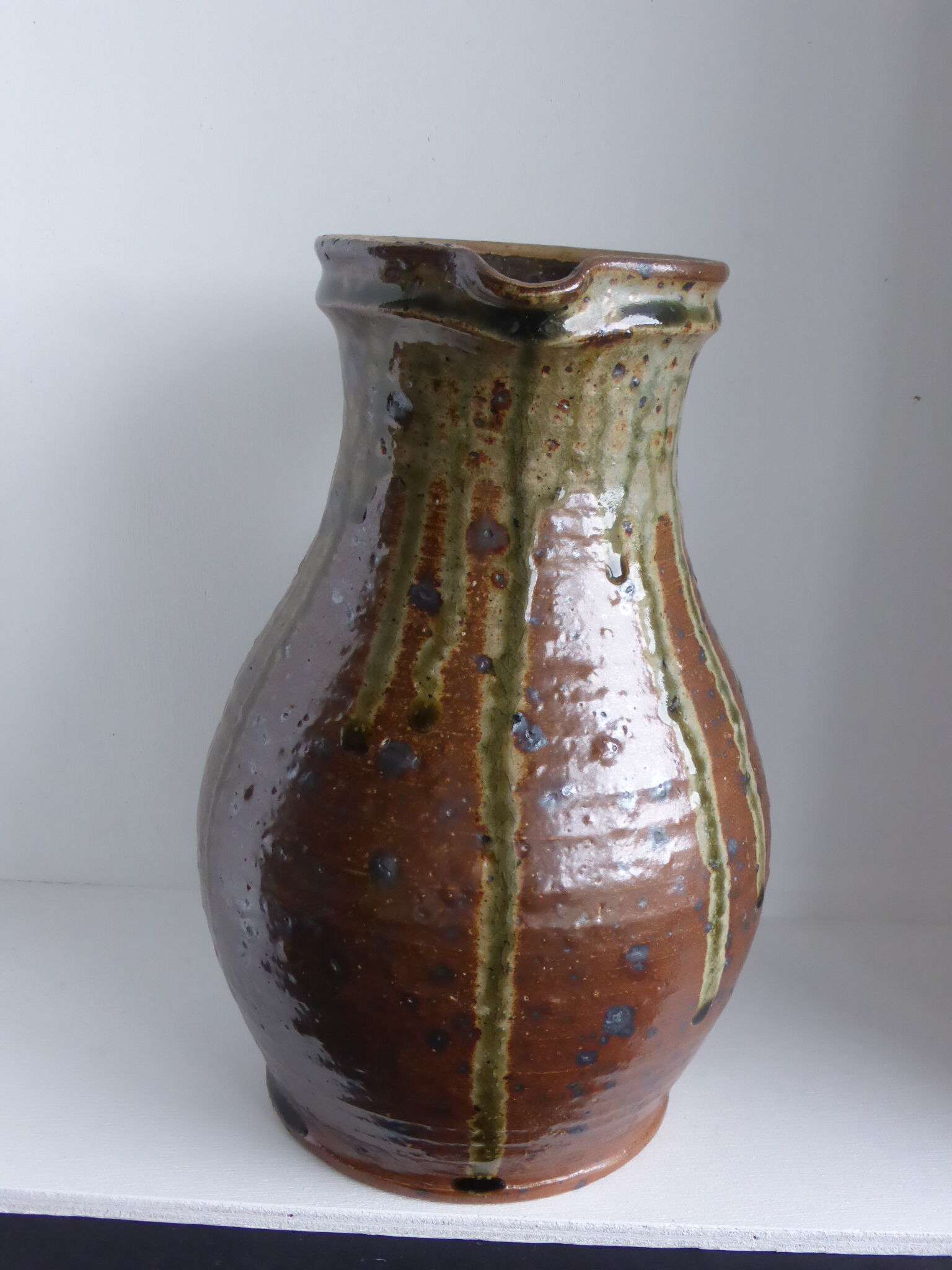 Old pitcher in brown sandstone with green drippings