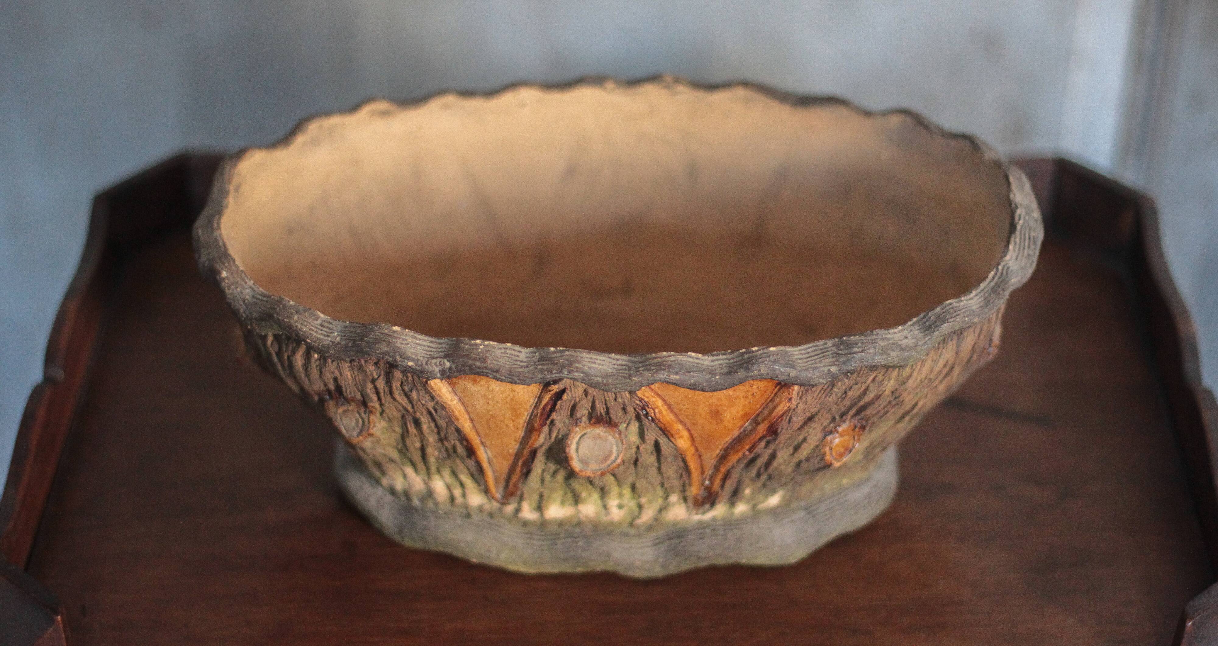 Terracotta planter in a brutalist style resembling a tree trunk, pot cover, countryside.