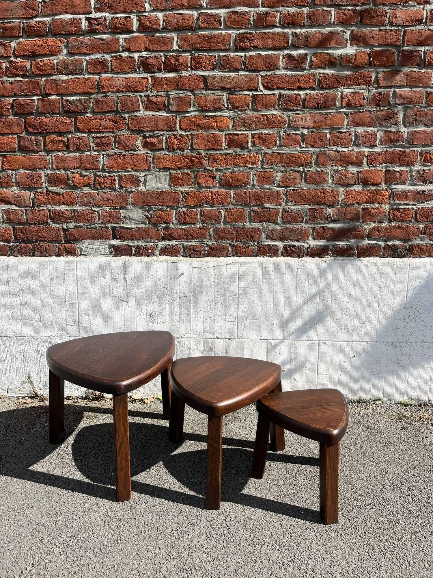 Nested tripod tables made of solid wood, in a modernist brutalist style.