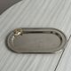 Small stainless steel tray with knot pattern.