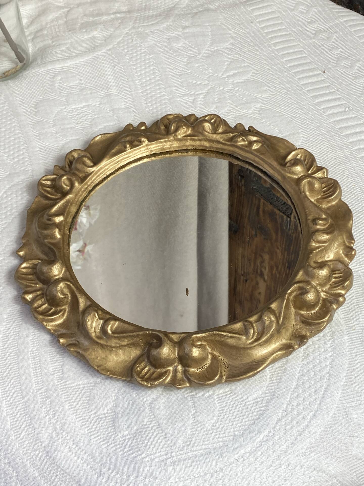 Round wooden mirror in golden colour.