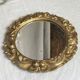 Round wooden mirror in golden colour.