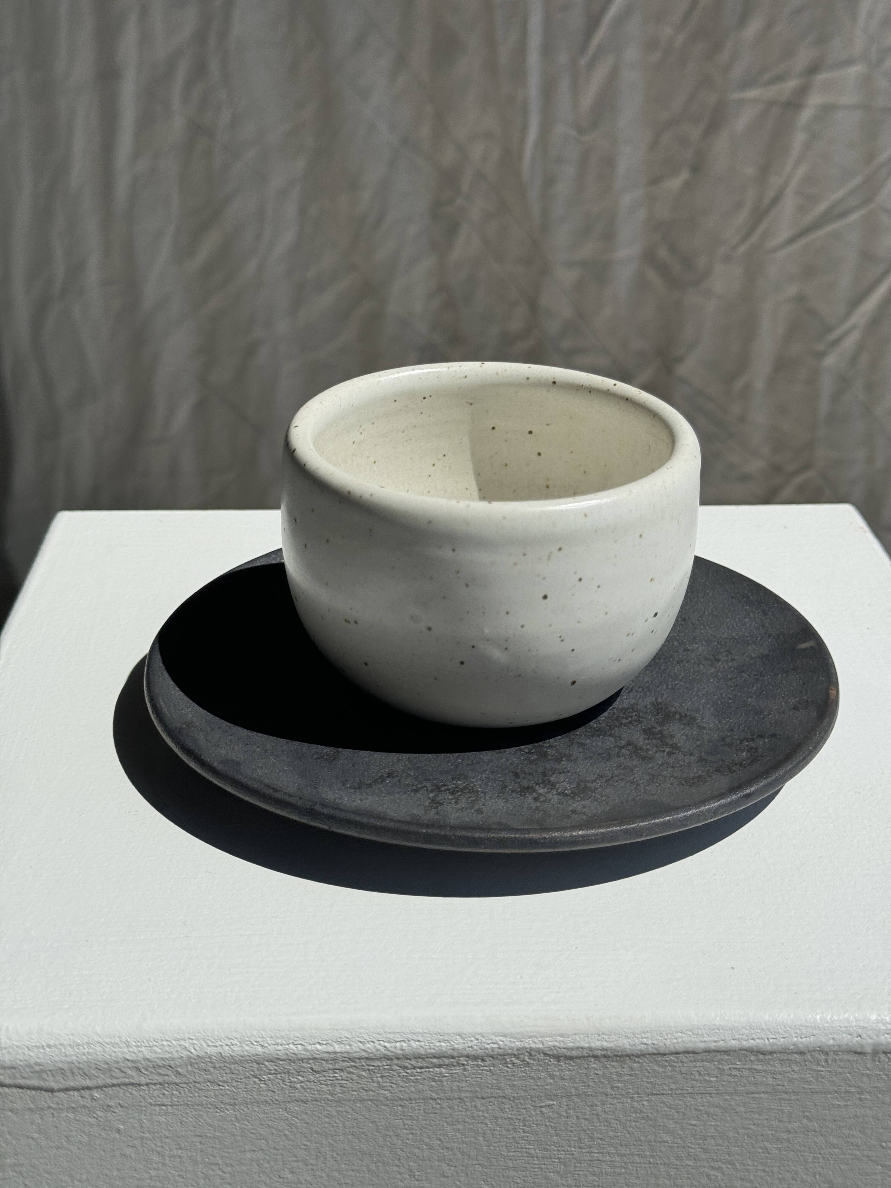 White Indonesian ceramic cup and gray saucer