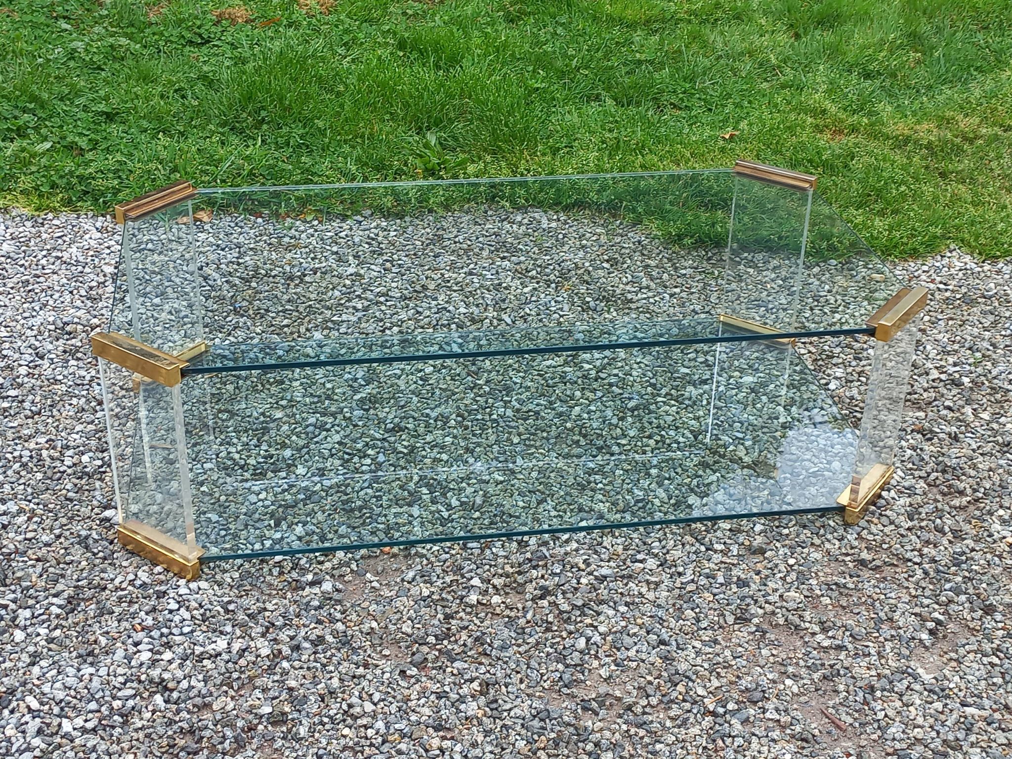 1970s designer coffee table in glass, plexiglass, and gold metal.