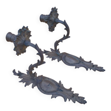 Pair of wall sconces in bronze candle holders with leaf medallion decoration.