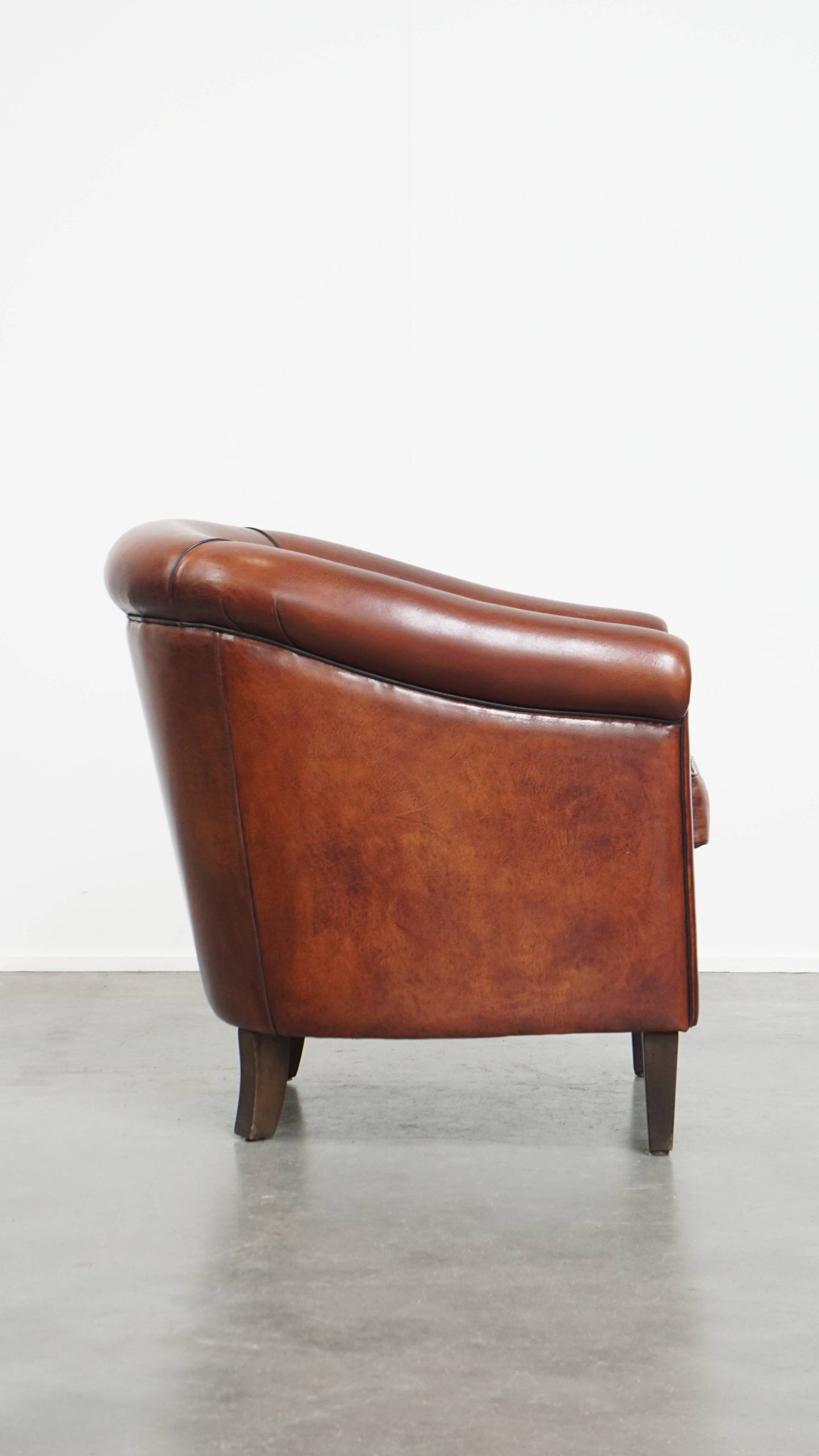 Sheepskin club armchair in a warm deep colour finished with black piping