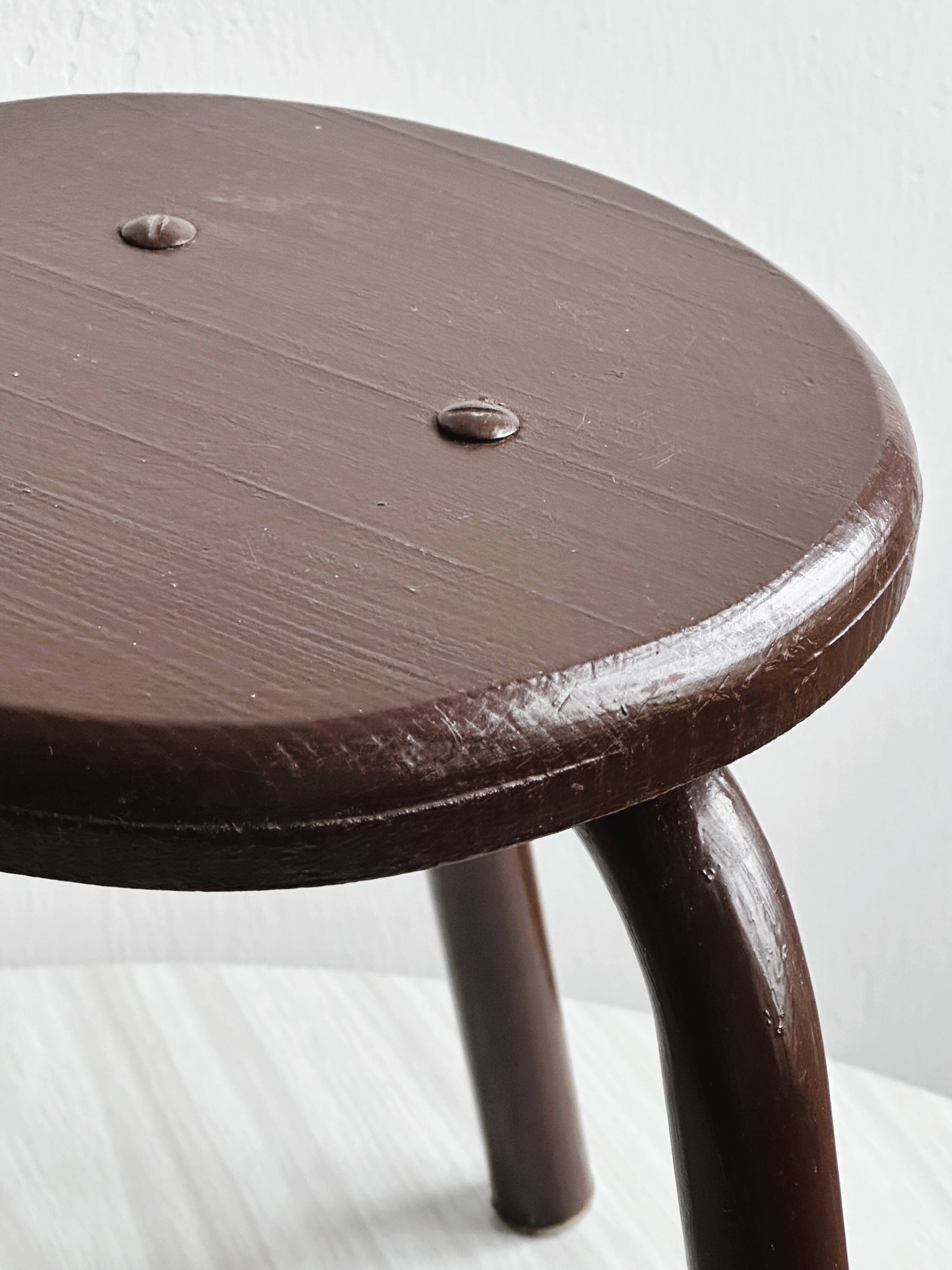 Dark brown metal stool, minimalist three-legged design