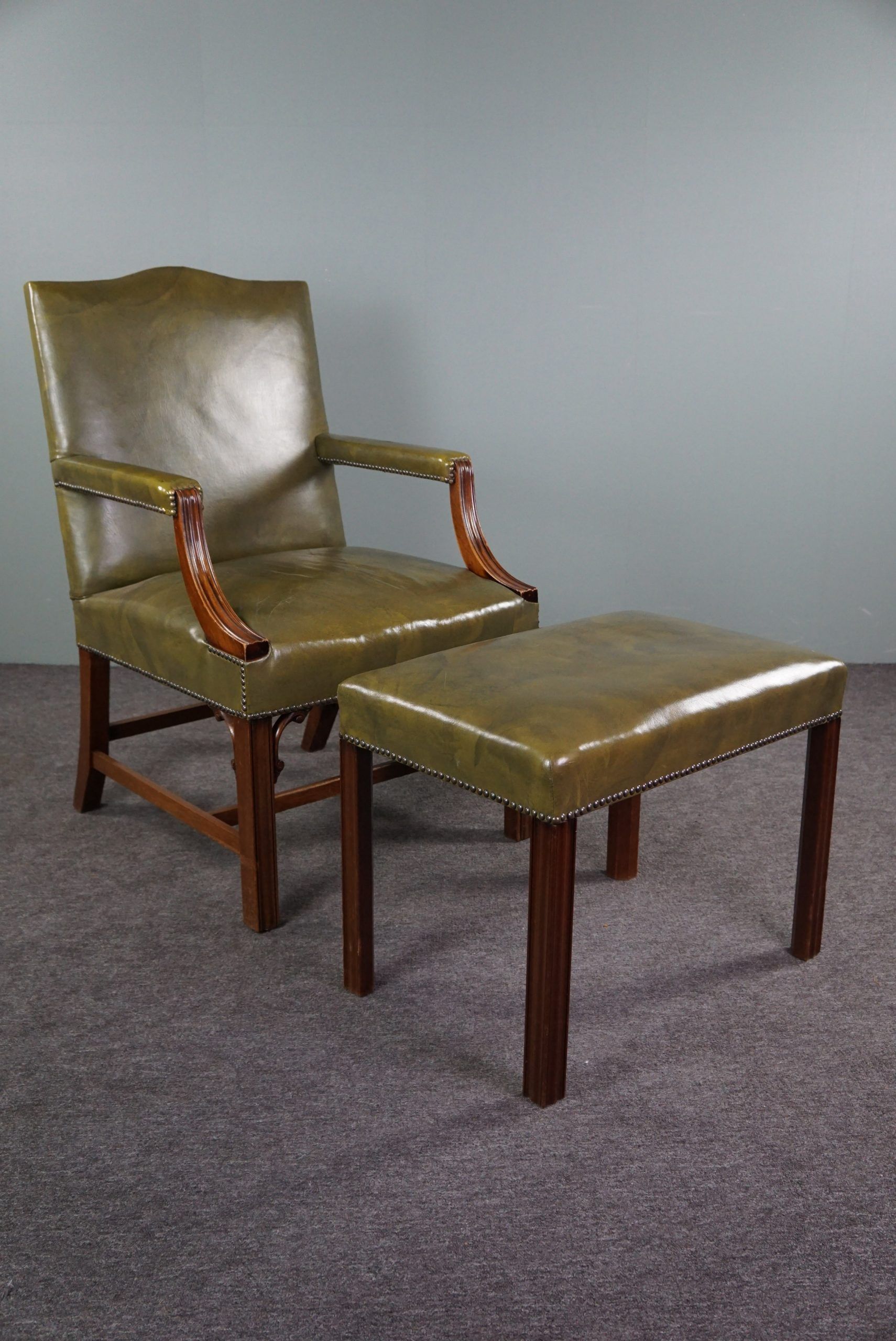 Elegant armchair and footrest in English green leather