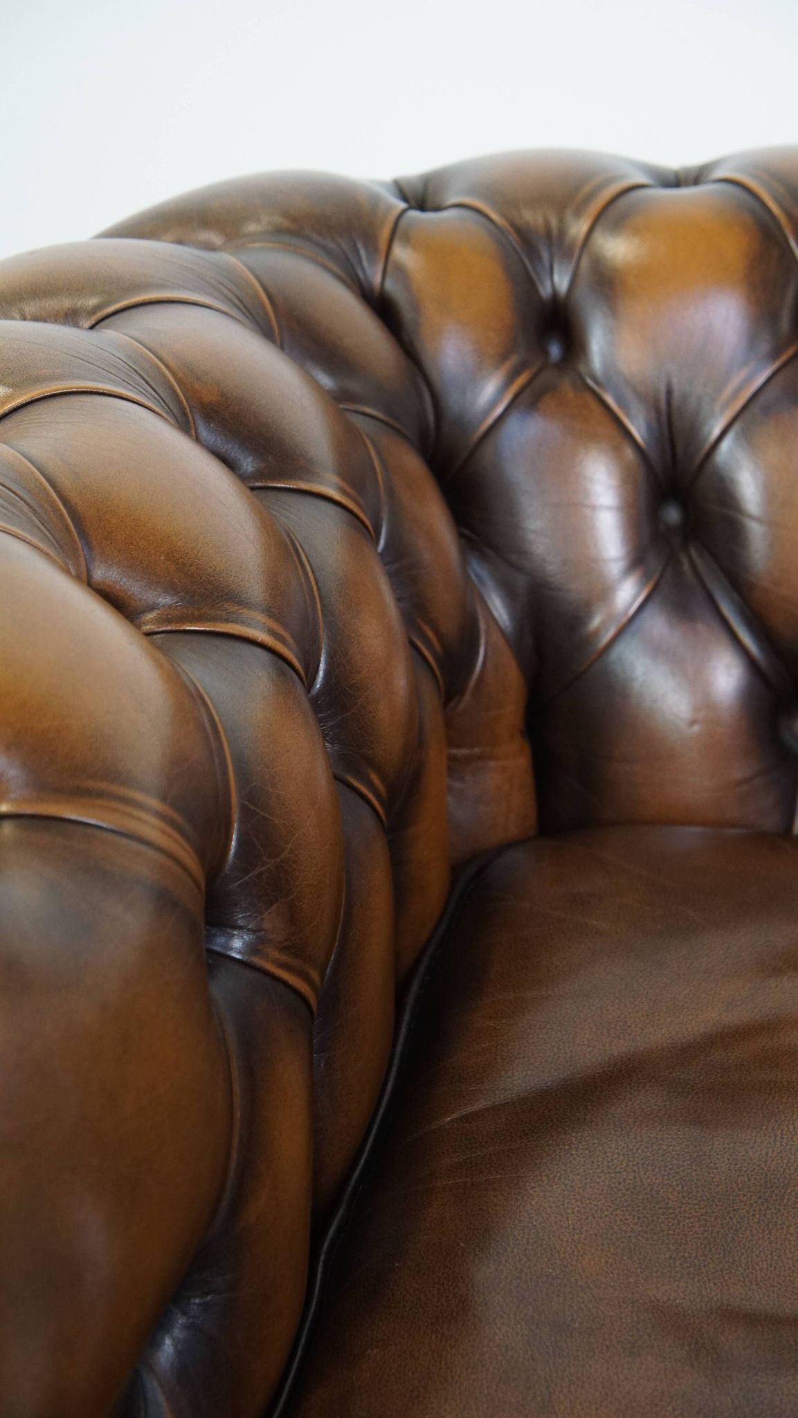A well-maintained cowhide leather English Chesterfield armchair