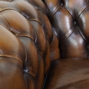 A well-maintained cowhide leather English Chesterfield armchair