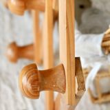 Antique wall-mounted coat rack accordion in dark pine, 10 wooden hooks.