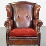 Sheep leather wingback chair with a red corduroy seat cushion and patina