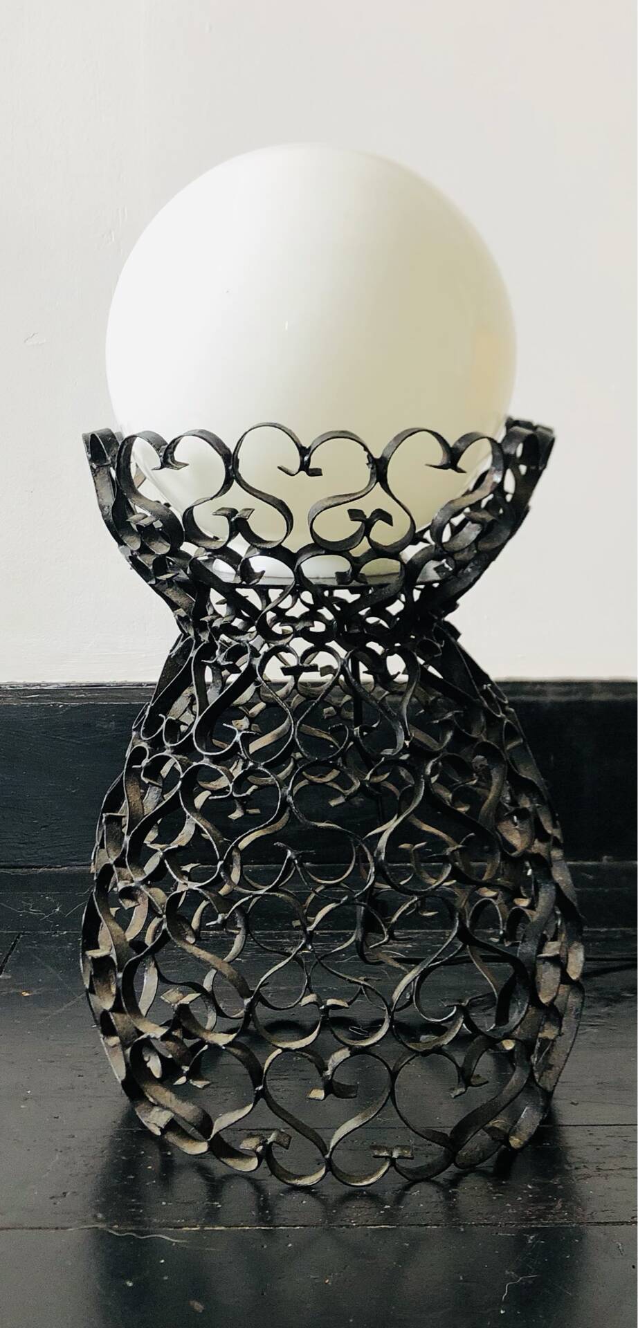 Handcrafted wrought iron lamp with a white opaline globe.