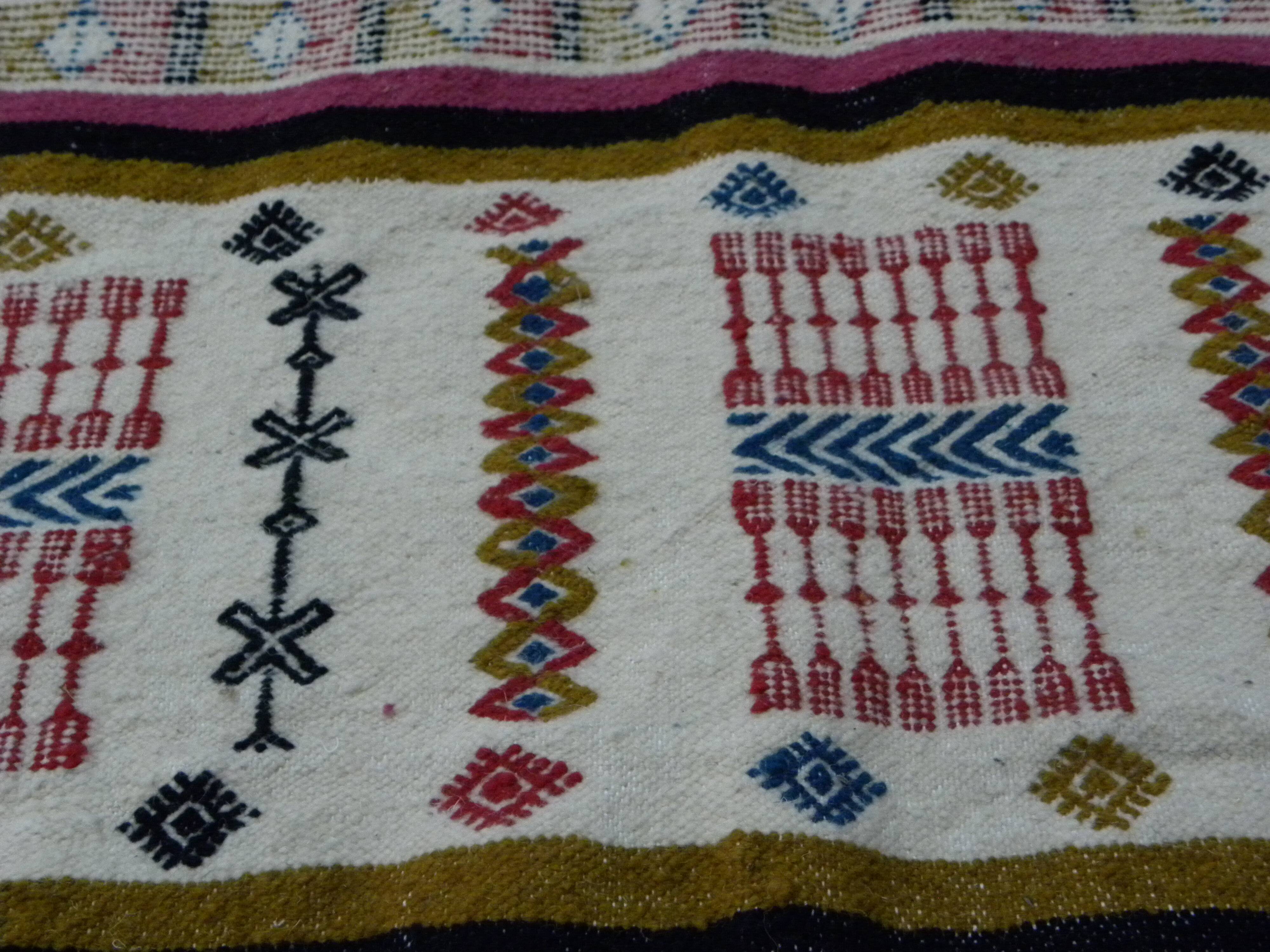 Handmade Berber kilim rug with multicoloured tribal motifs.