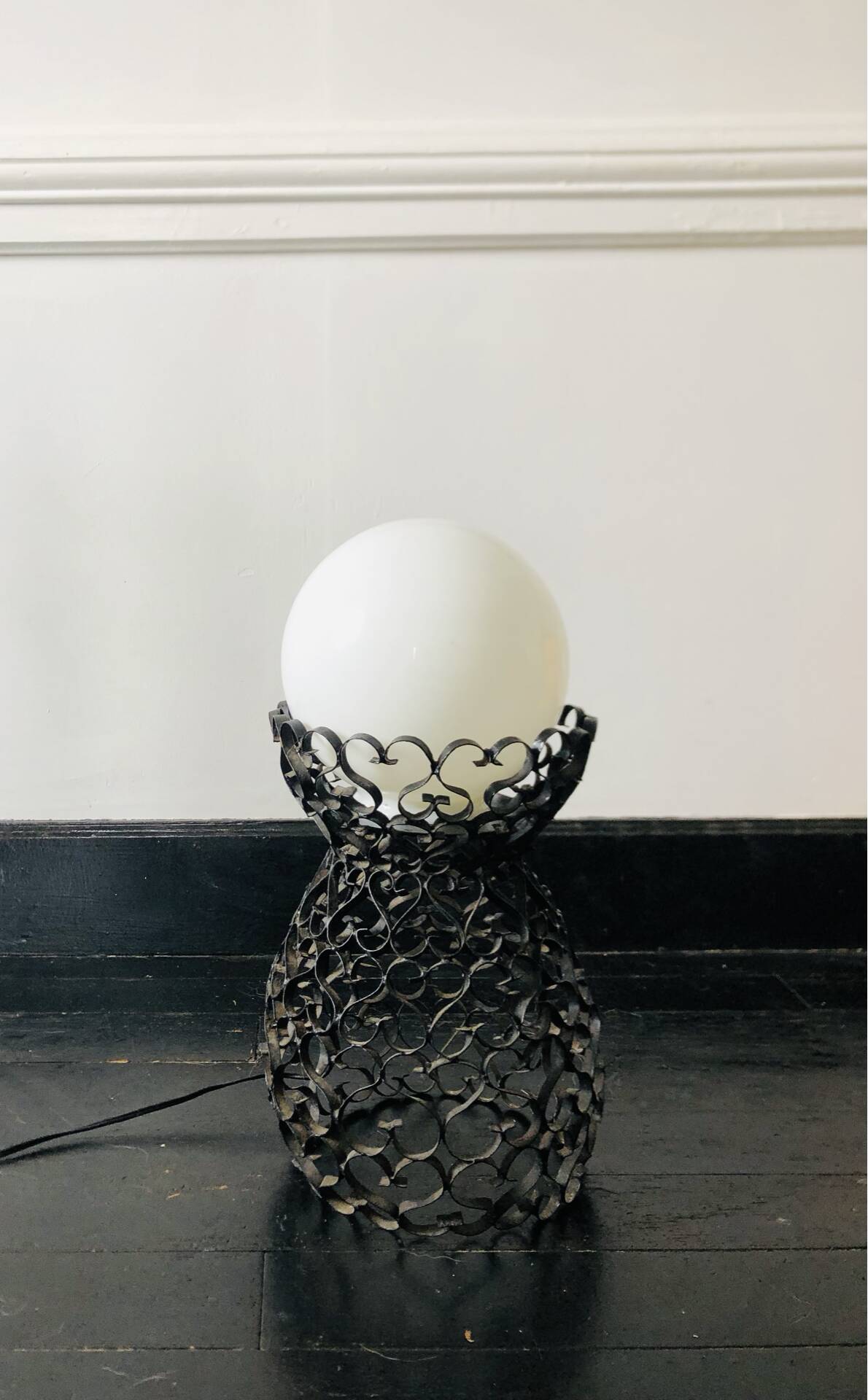 Handcrafted wrought iron lamp with a white opaline globe.