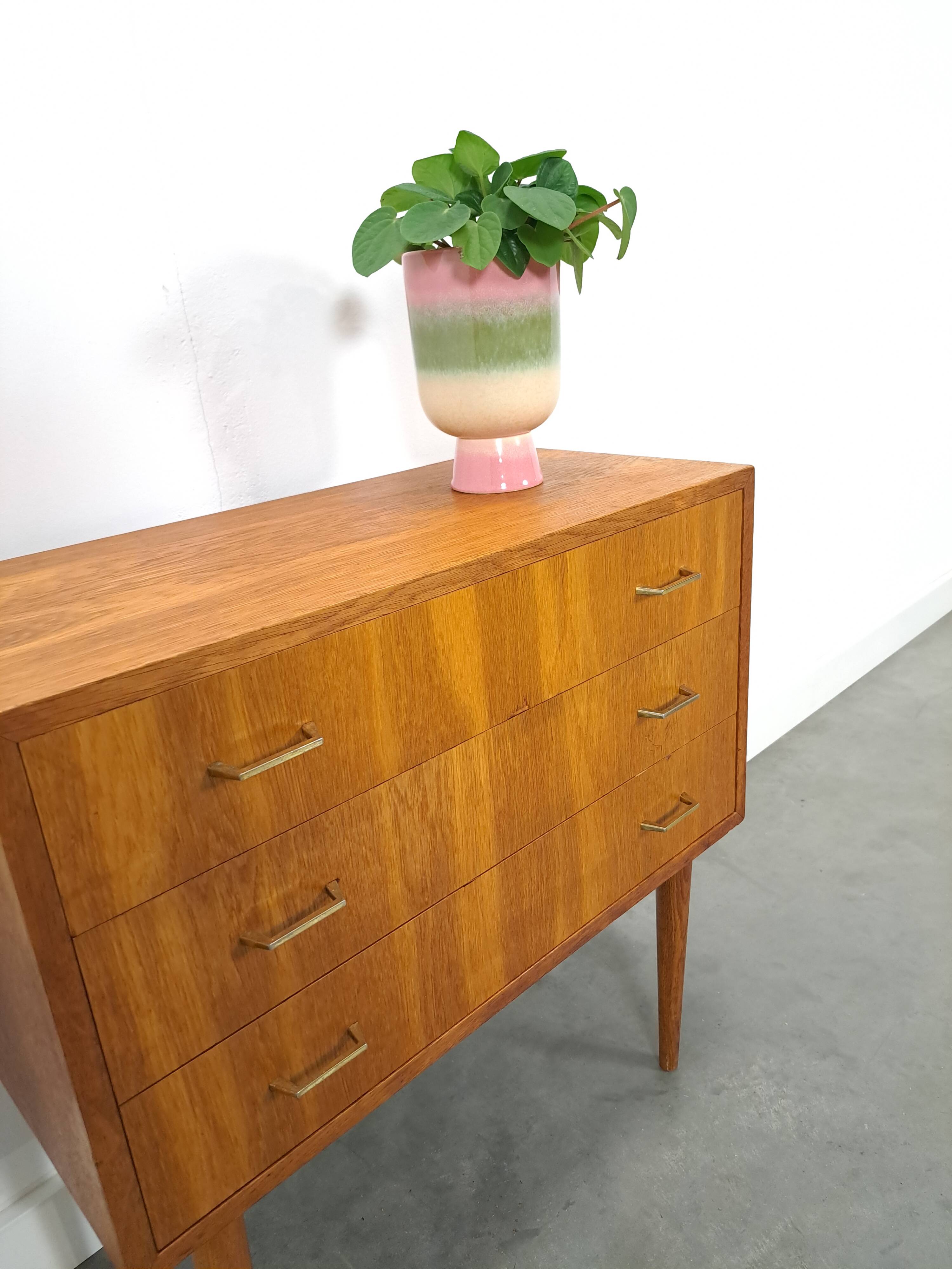 Commode danoise avec de hauts pieds et des poignées dorées.