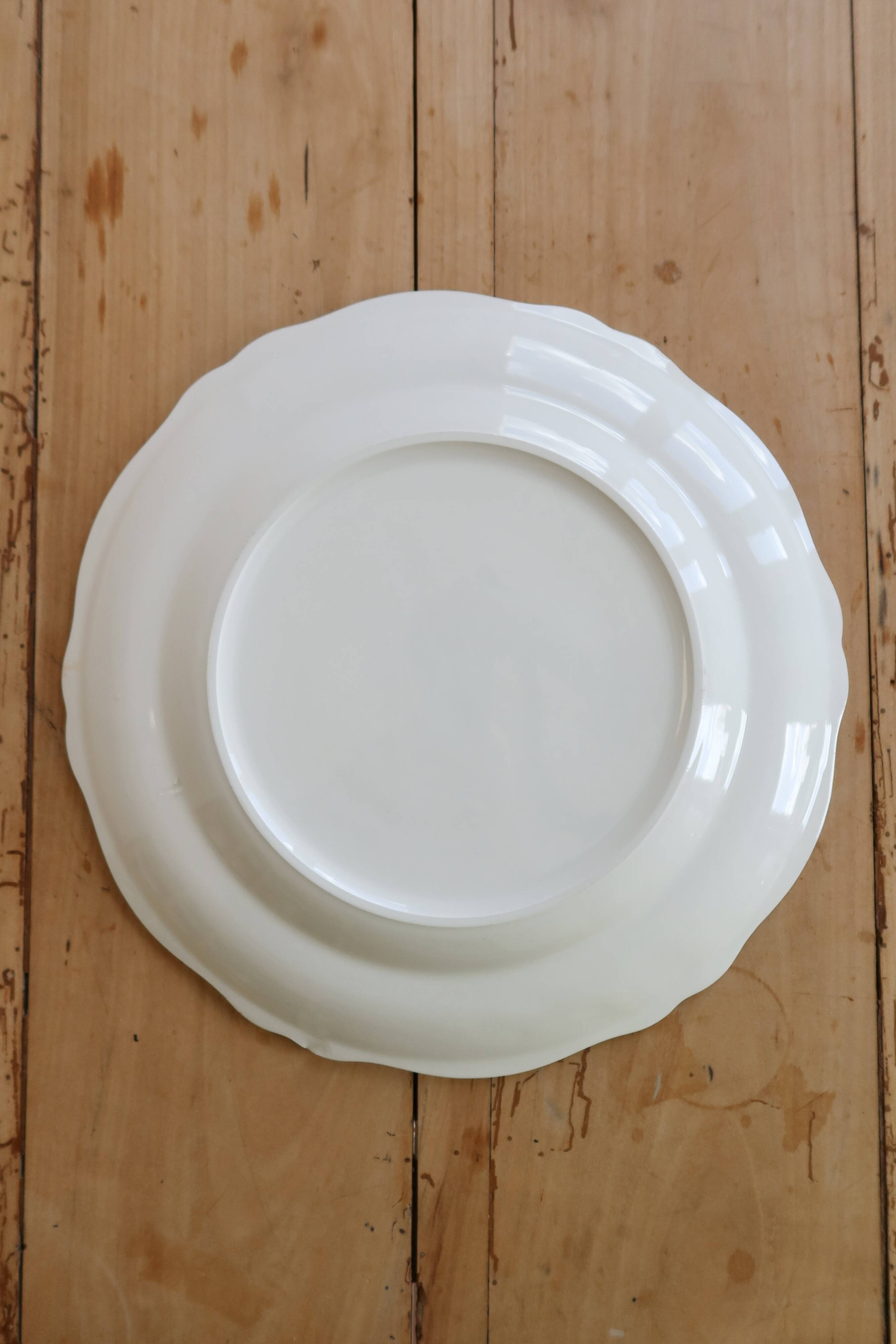 Round vintage ivory earthenware serving dish with scalloped rim.