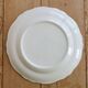 Round vintage ivory earthenware serving dish with scalloped rim.