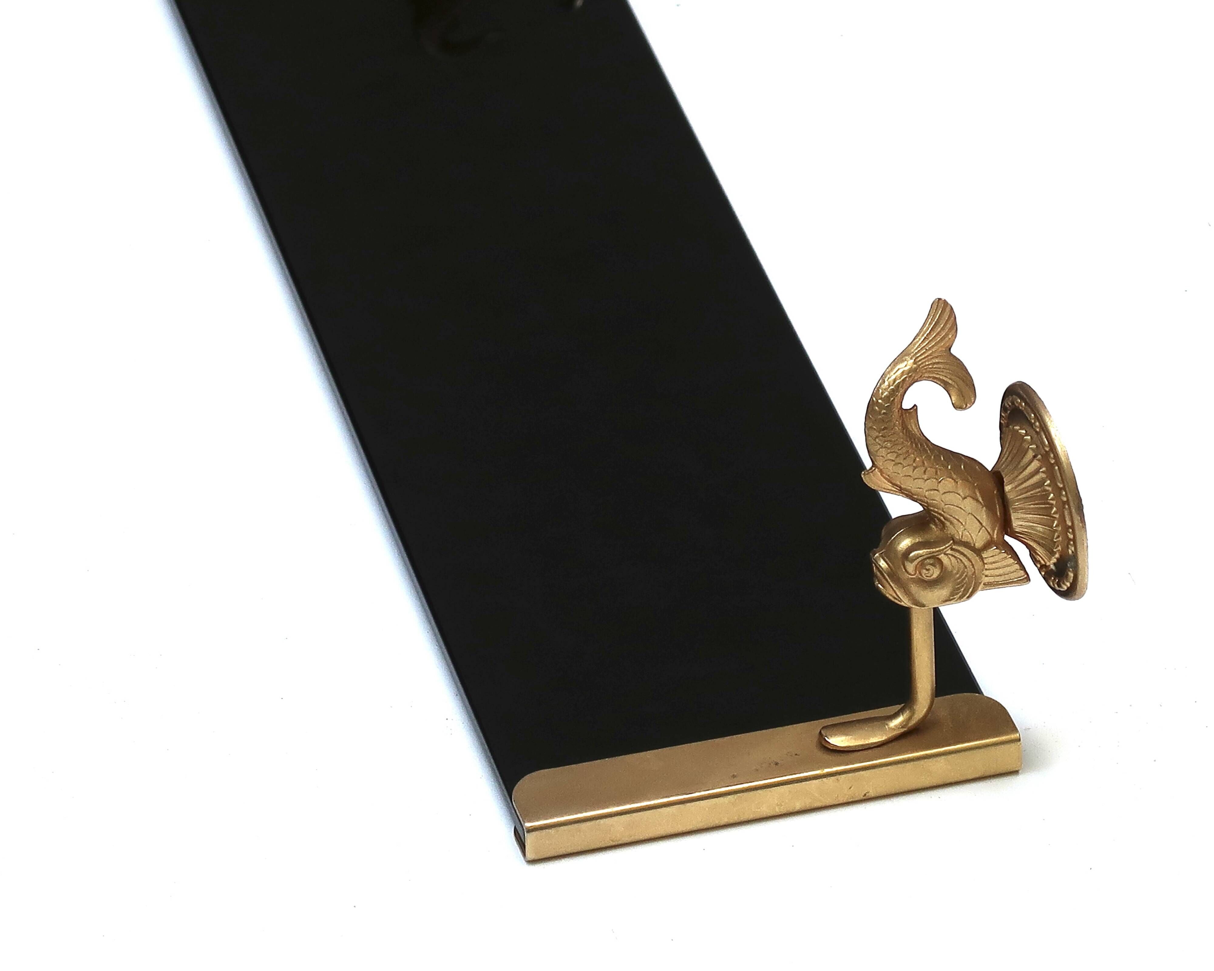 Wall shelf in gold metal and black glass adorned with fish.