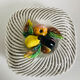 Covered basket in white woven ceramic and fruit slip.