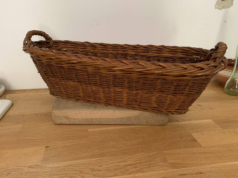 Vintage brown wicker baguette basket, elongated shape, with integrated handles.