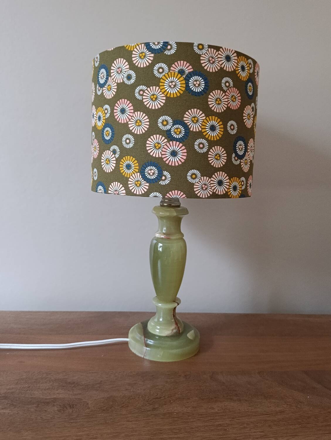 Table lamp with light green onyx base, fabric shade with a khaki background.