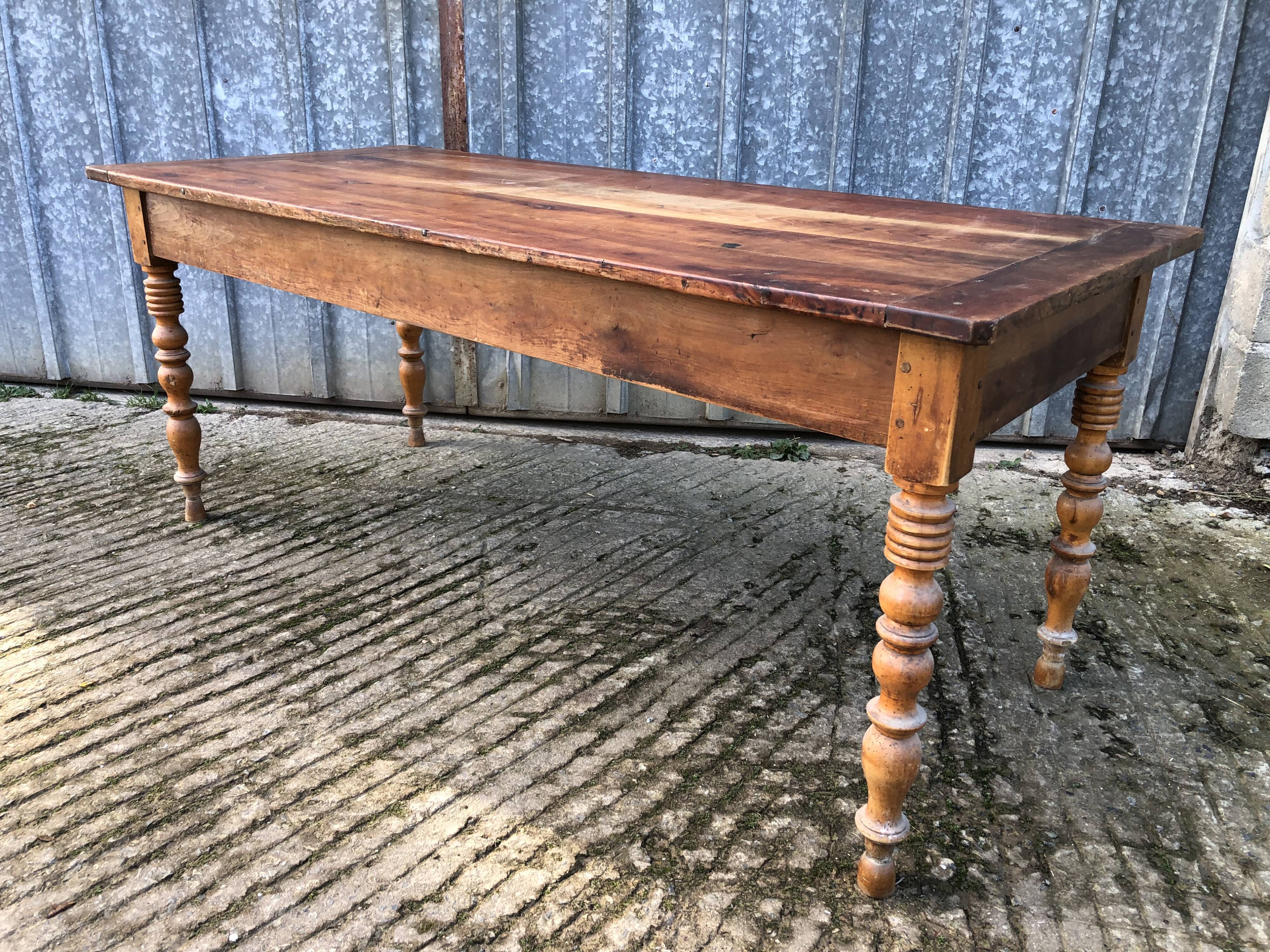 Antique farmhouse table in solid cherry wood with turned legs.