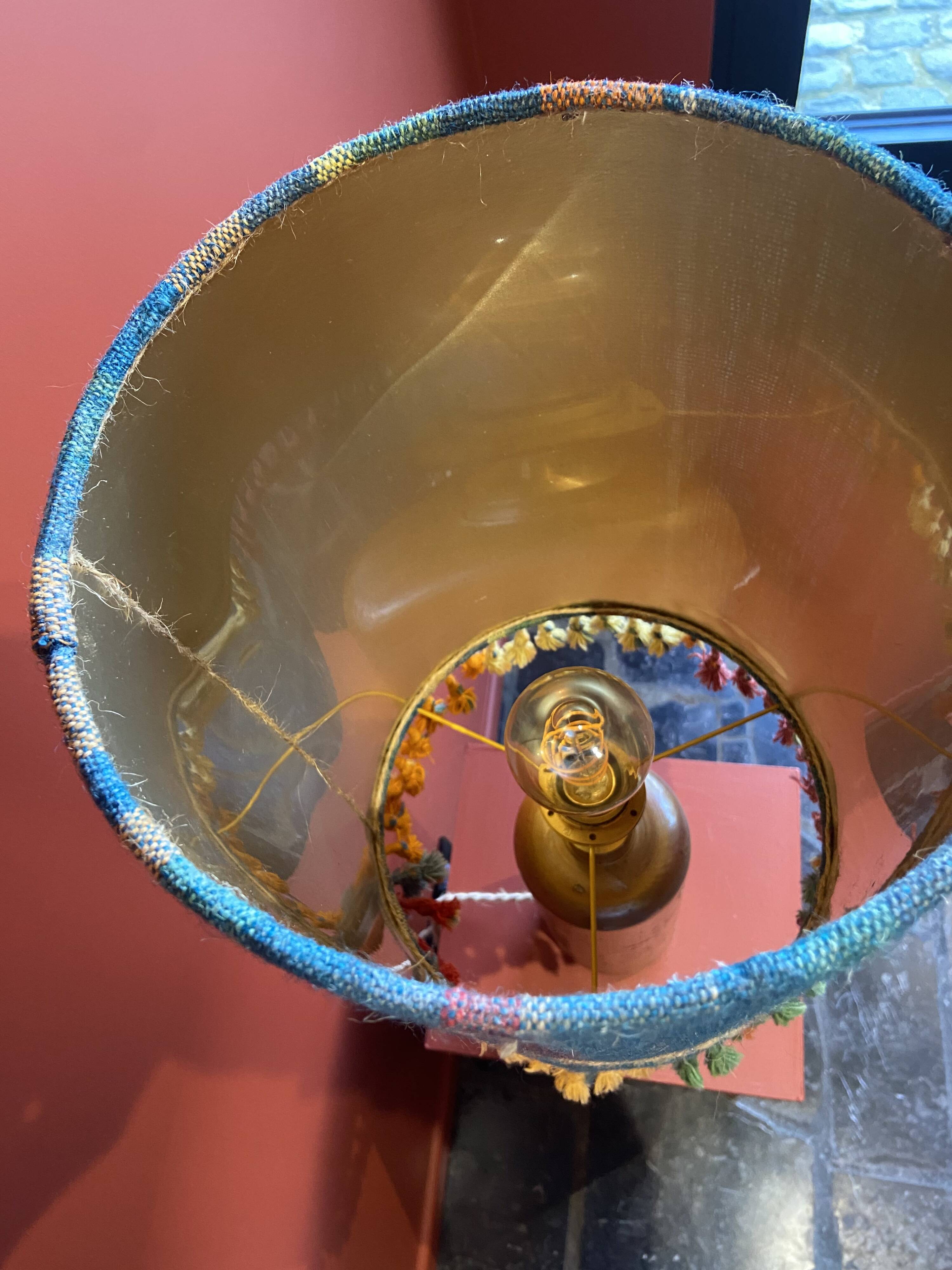 "Stoneware Bottle Lamp" with a multicoloured blue lampshade handwoven in India.