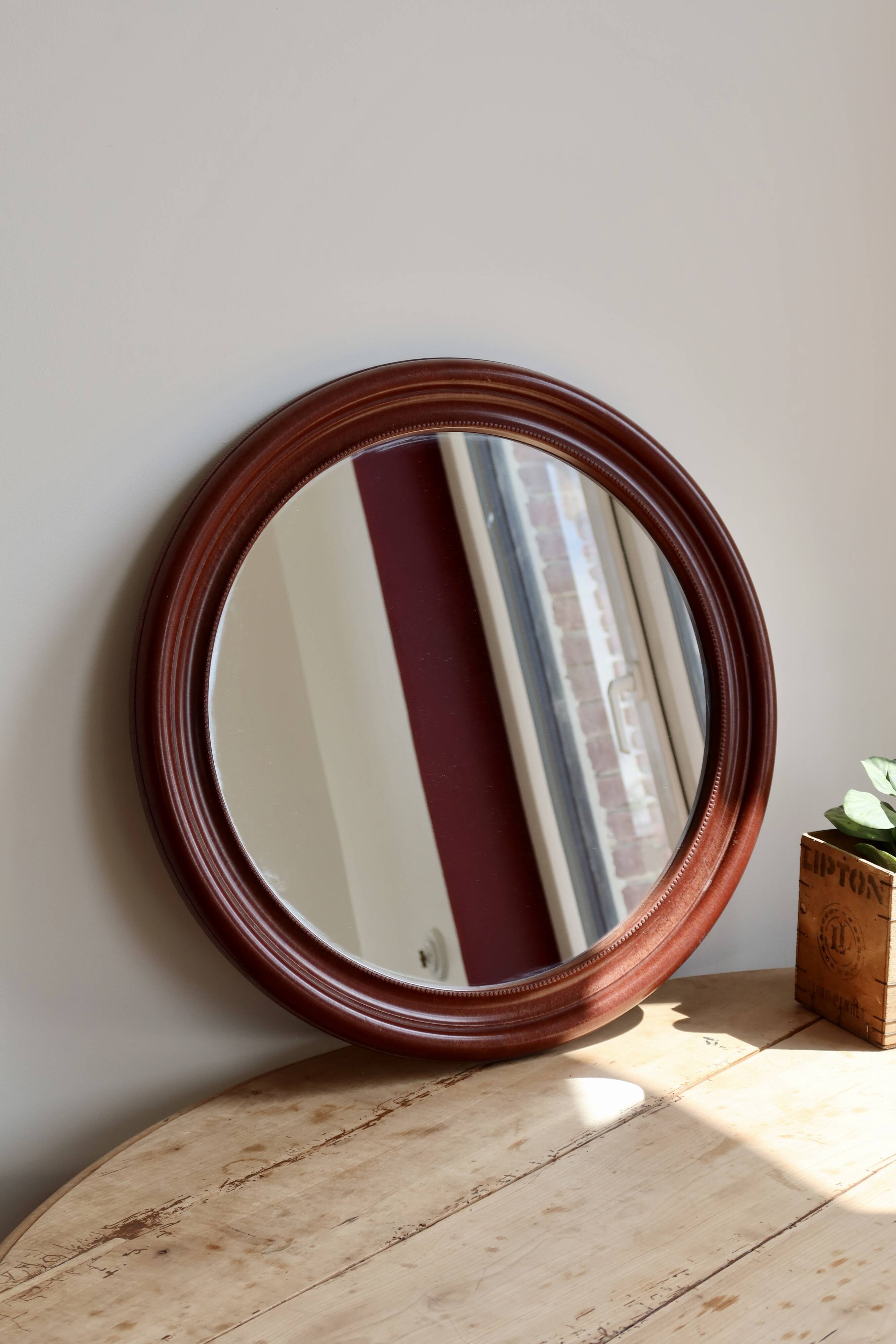 Round vintage mirror with mahogany wood effect frame.