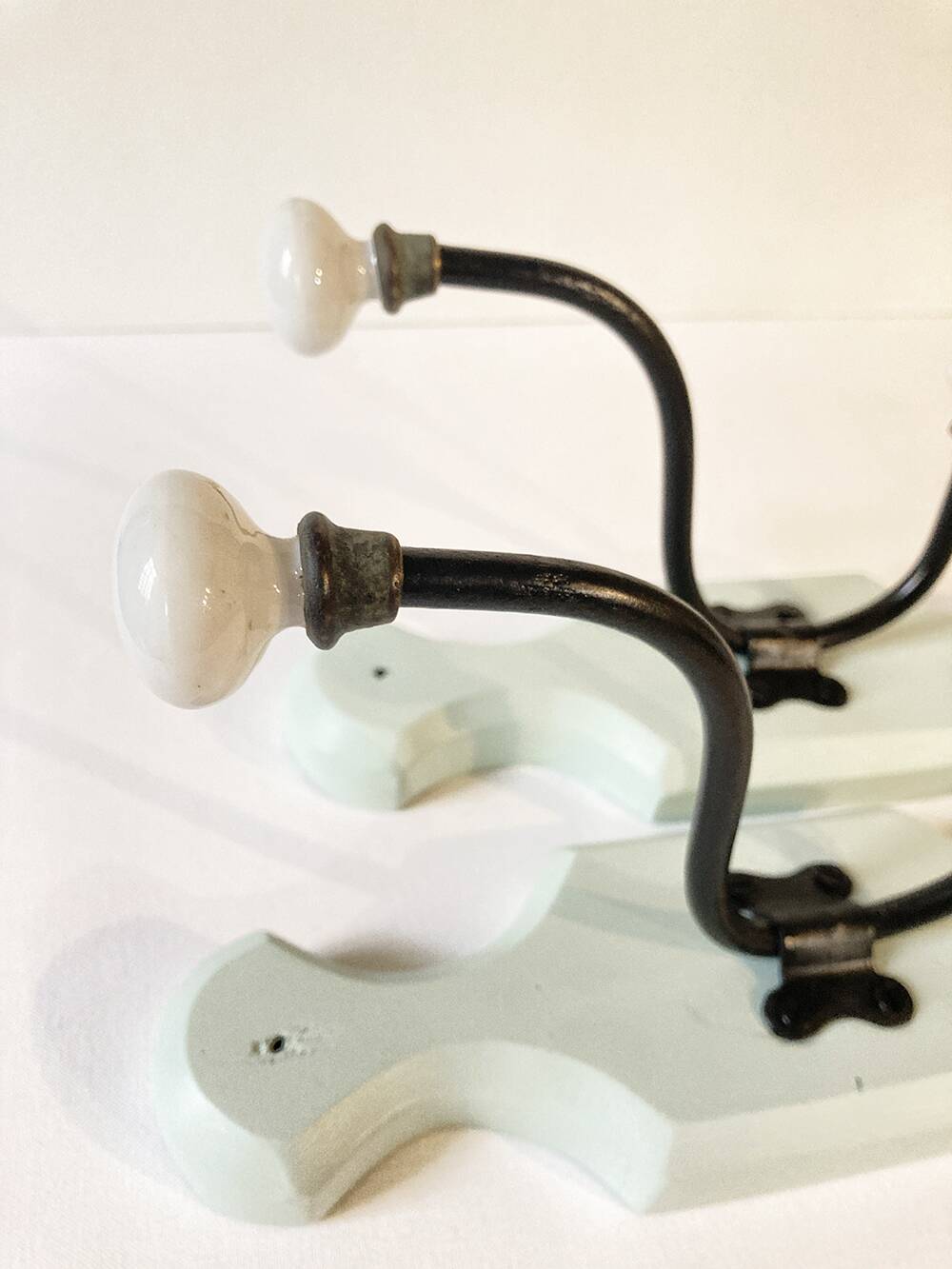 Antique metal and porcelain coat hooks, painted wooden support
