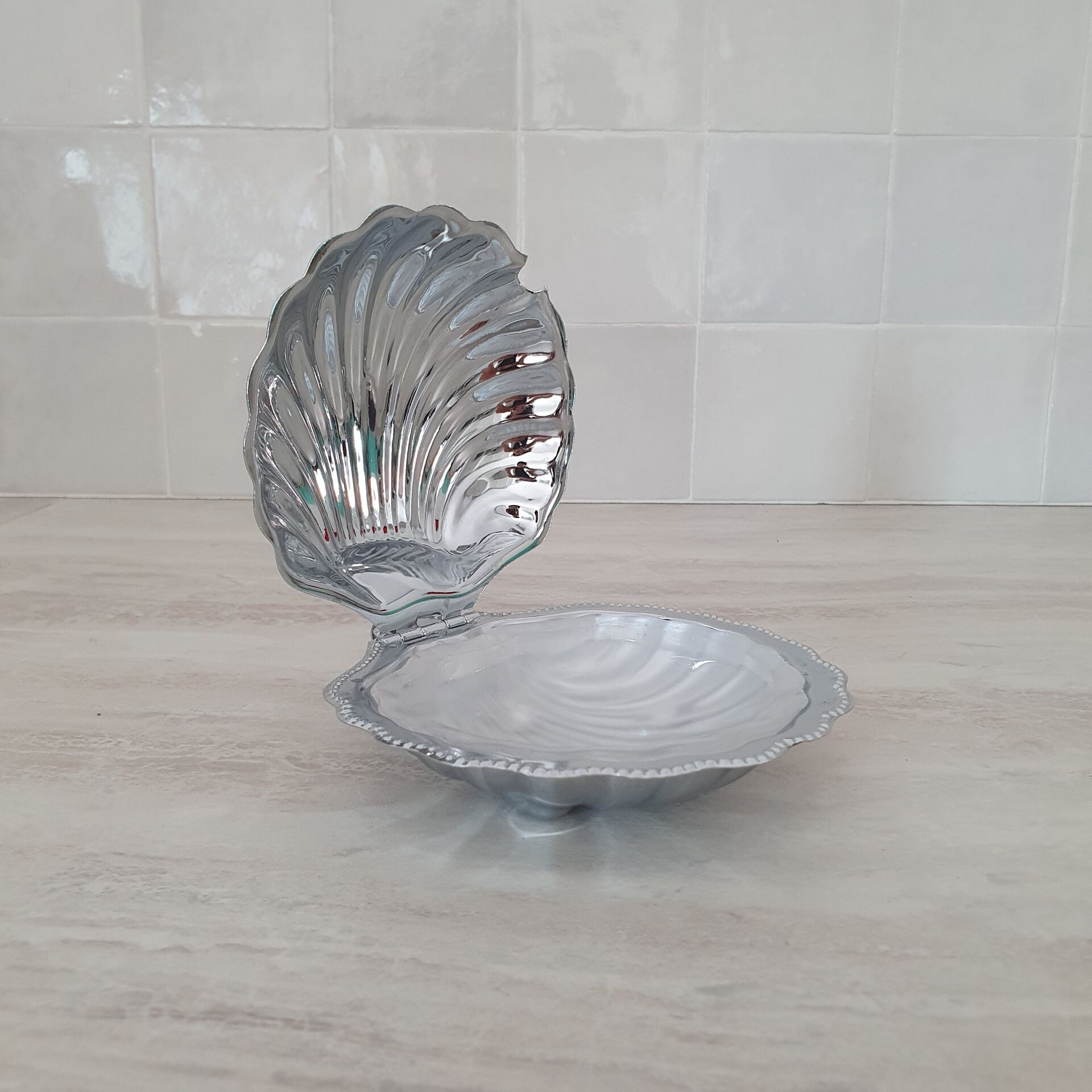 Shell-shaped butter dish in stainless steel and white glass bowl.