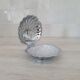 Shell-shaped butter dish in stainless steel and white glass bowl.
