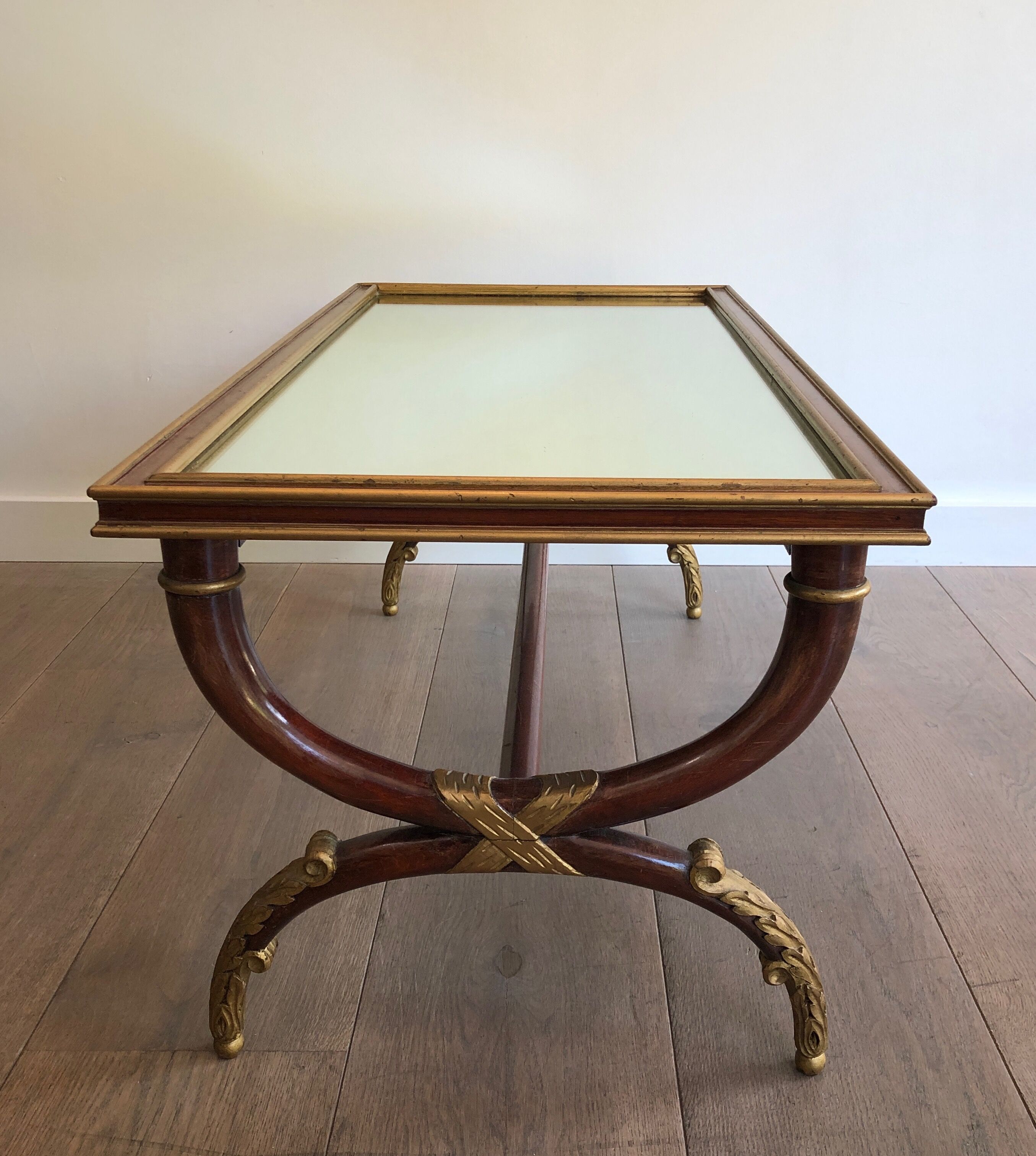 Coffee table in patinated and gilded carved wood with mirror top