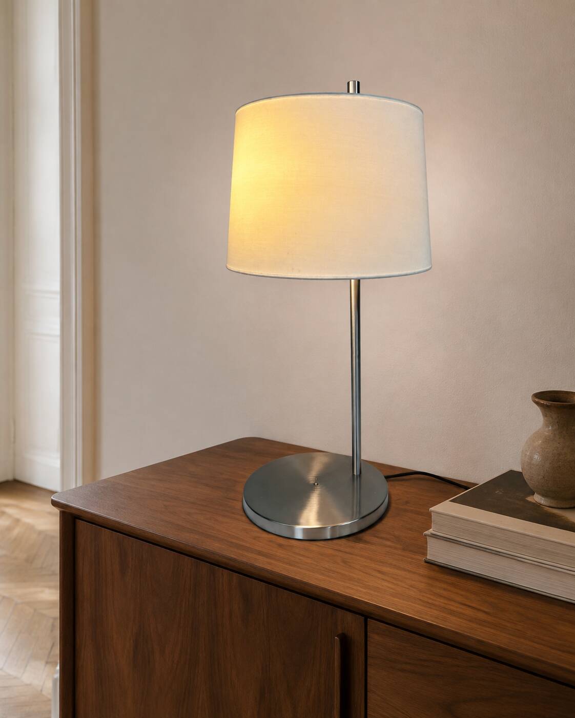 Large brushed metal table lamp with an ecru shade.