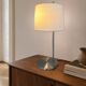 Large brushed metal table lamp with an ecru shade.