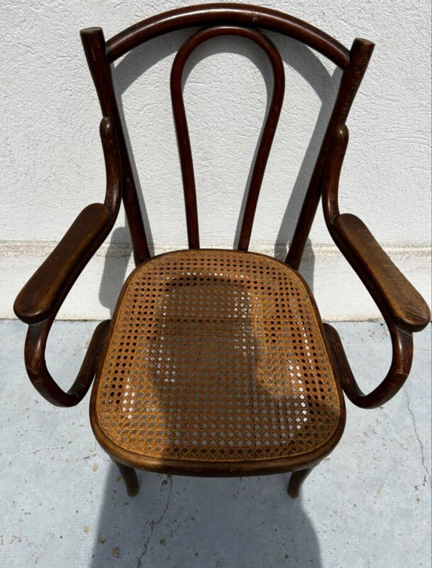 Thonet armchair stamped with curved wooden armrests and caning from the 19th century.