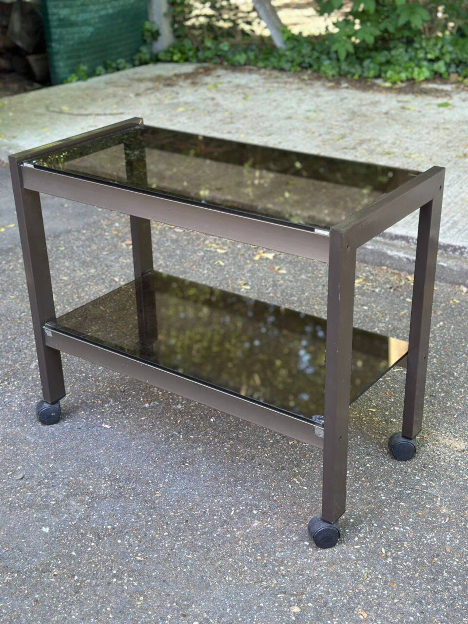 Vintage 1970s rolling bar cart made of metal and smoked glass.