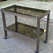 Vintage 1970s rolling bar cart made of metal and smoked glass.