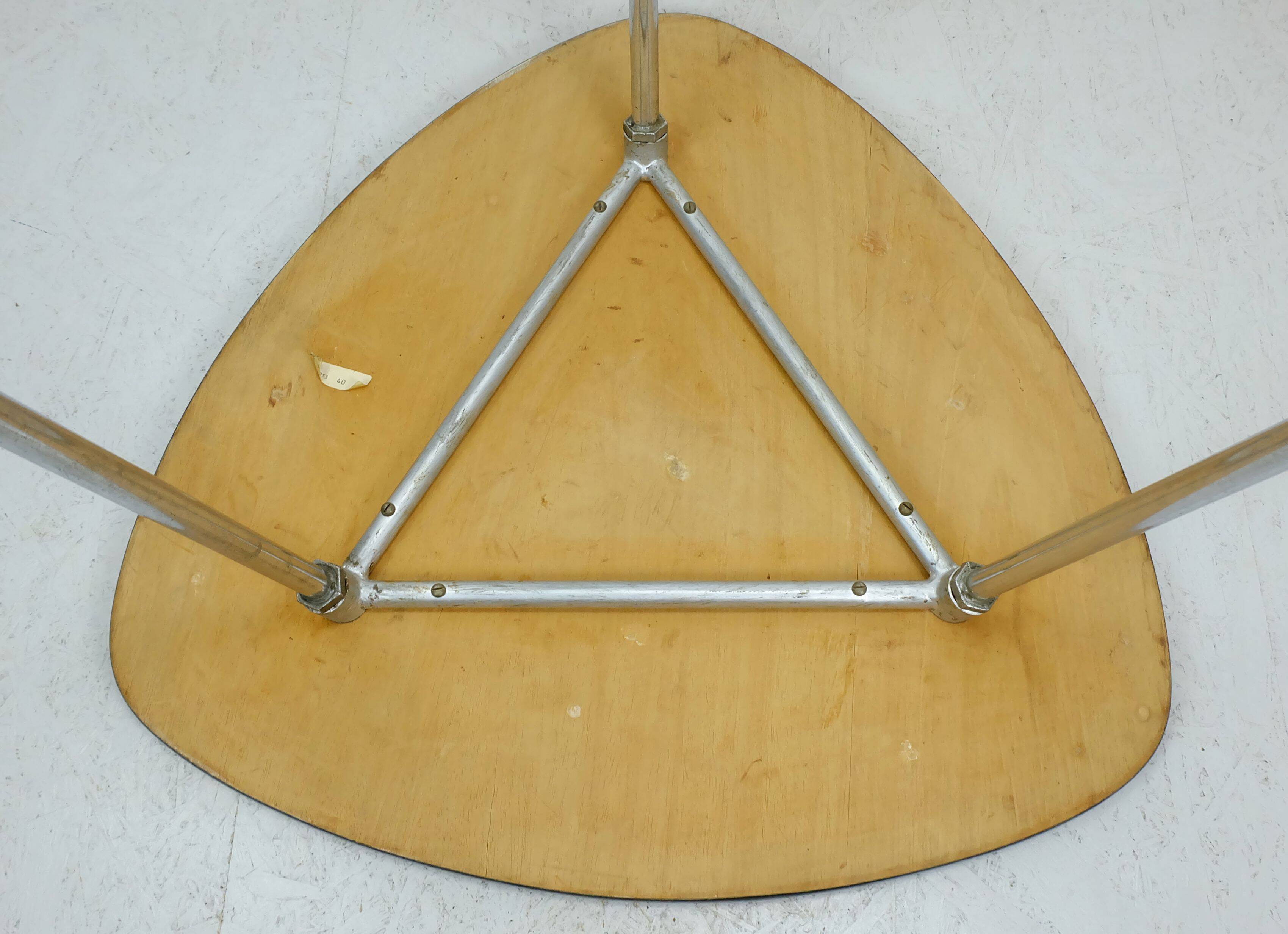 Table basse des années 1950 à trois pieds avec un plateau en formica et des pieds en chrome inclinés.