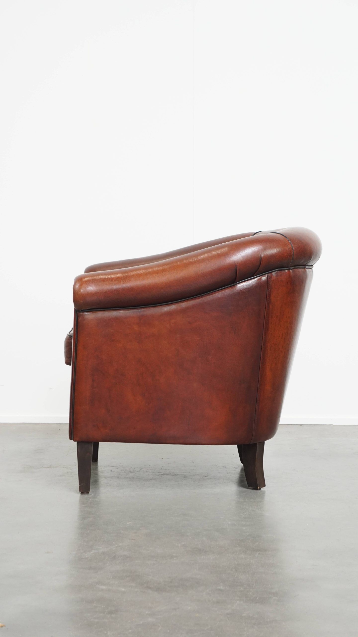 Sheepskin club armchair in a warm deep colour finished with black piping