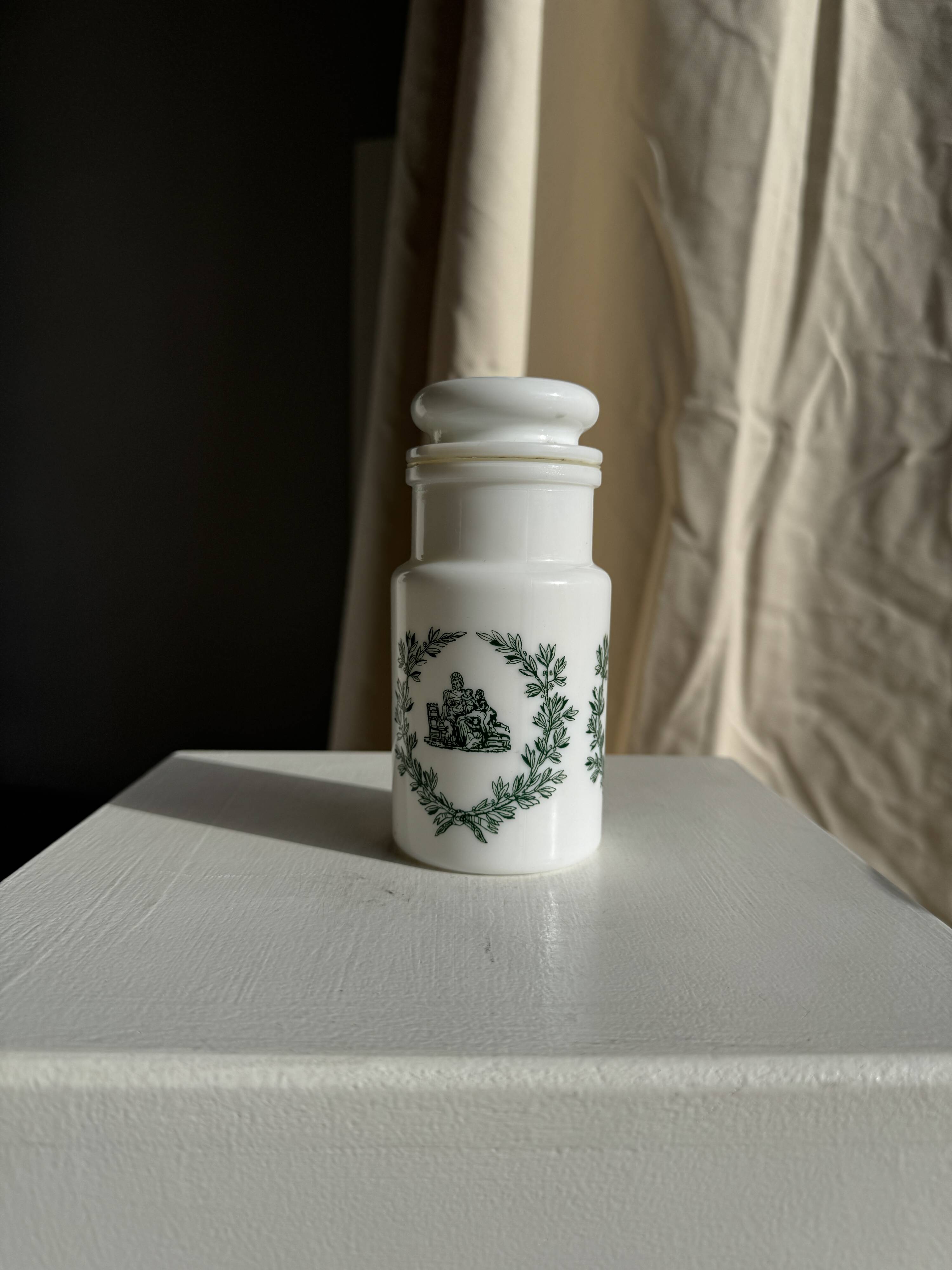 A pair of white glass bottles with Italian green patterns.