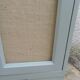Small vintage green-grey piece of furniture, with 2 doors covered in burlap.