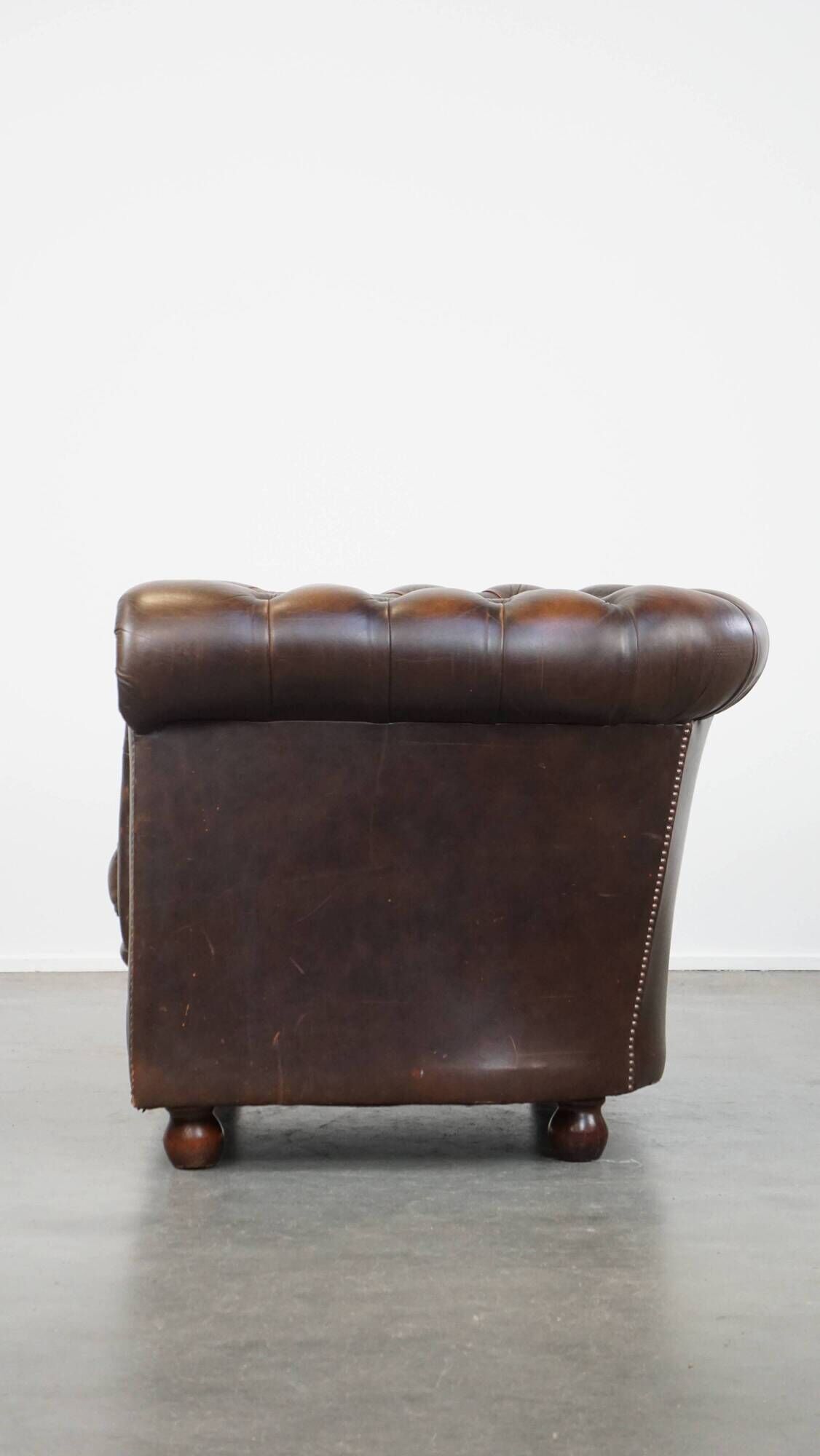 Cowhide English Chesterfield armchair with ball legs and timeless finish