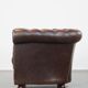 Cowhide English Chesterfield armchair with ball legs and timeless finish