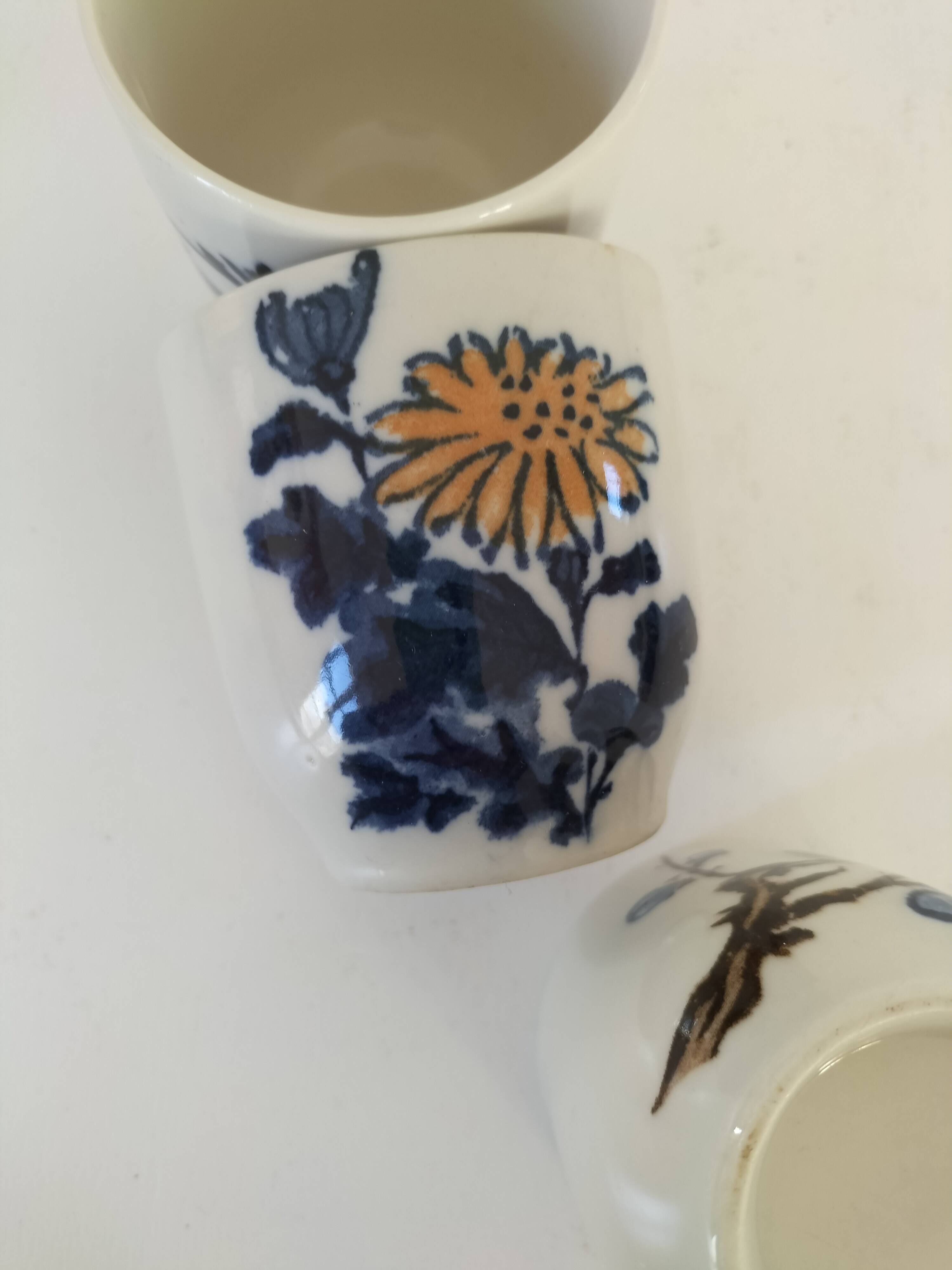 Set of three hand-painted porcelain cups with floral patterns.