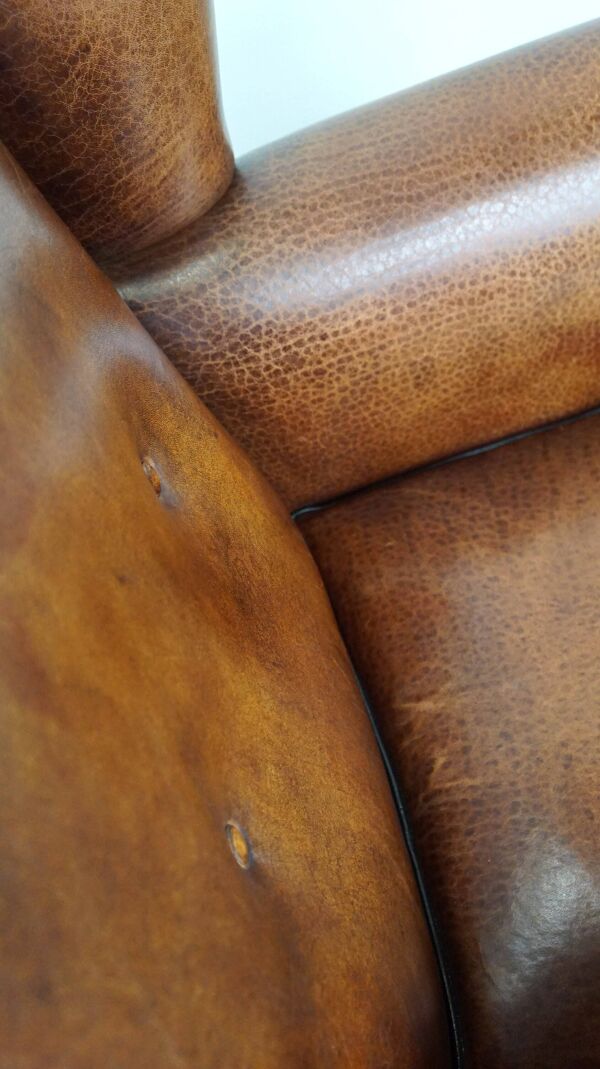 Fauteuil à oreilles en cuir de mouton, avec clous et passepoil noir