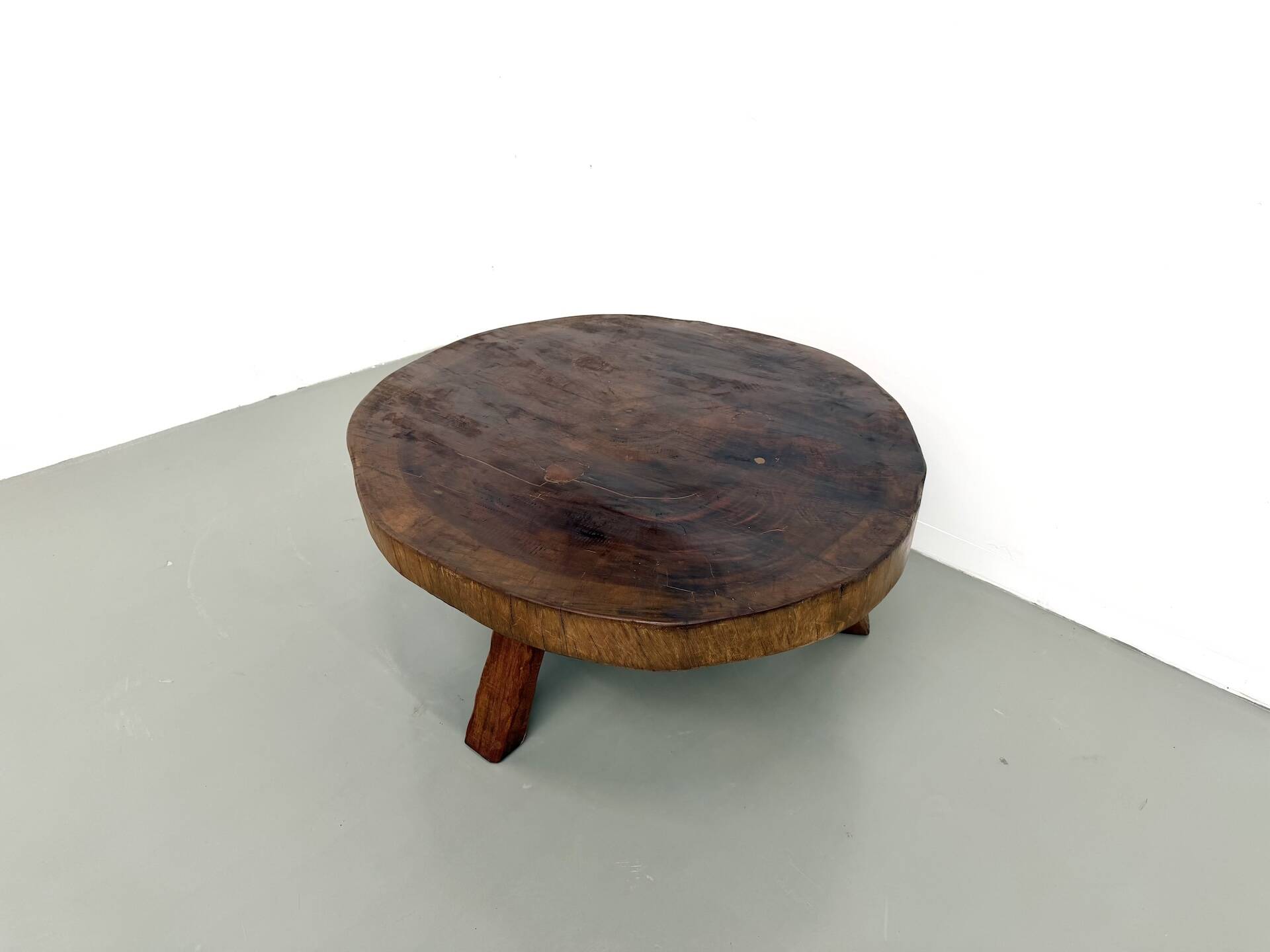 Brutalist coffee table in solid teak, monolithic slab, tripod base.