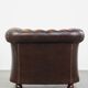 Cowhide English Chesterfield armchair with ball legs and timeless finish