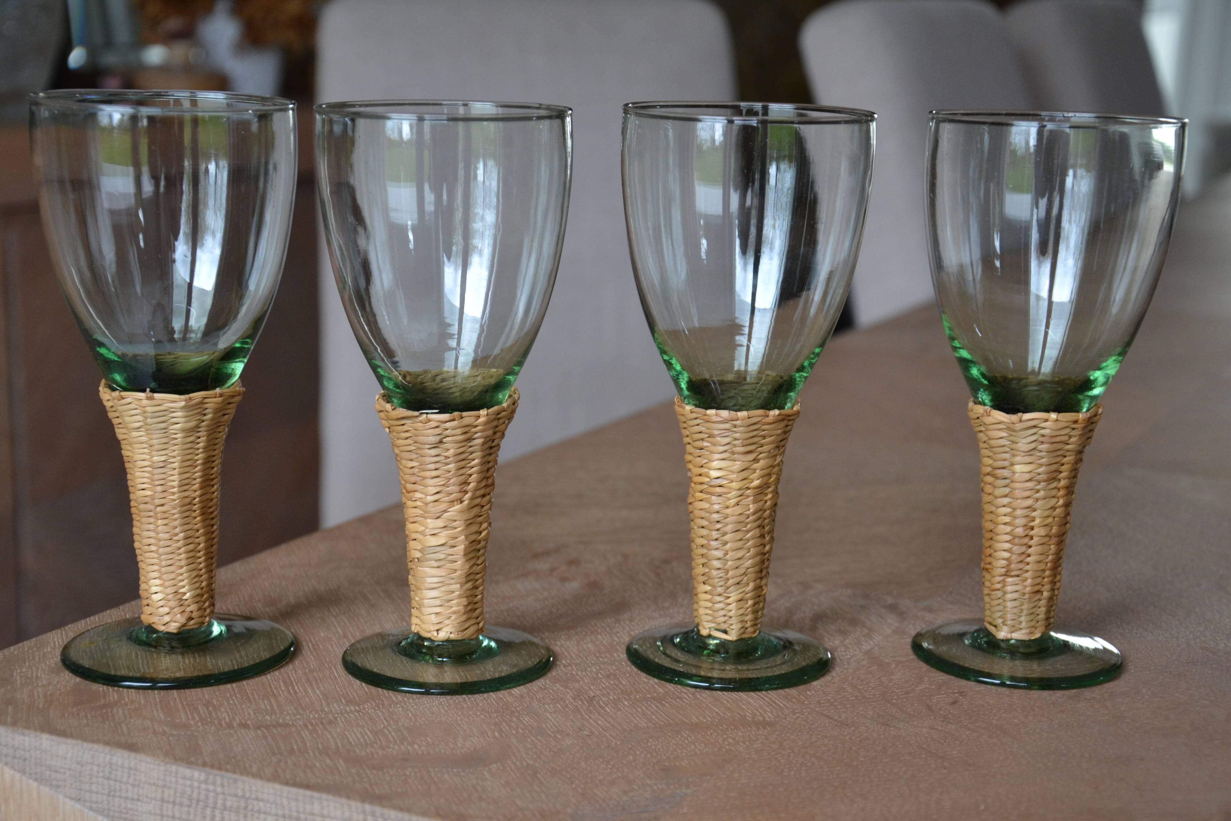 Four stemmed glasses surrounded by rattan.