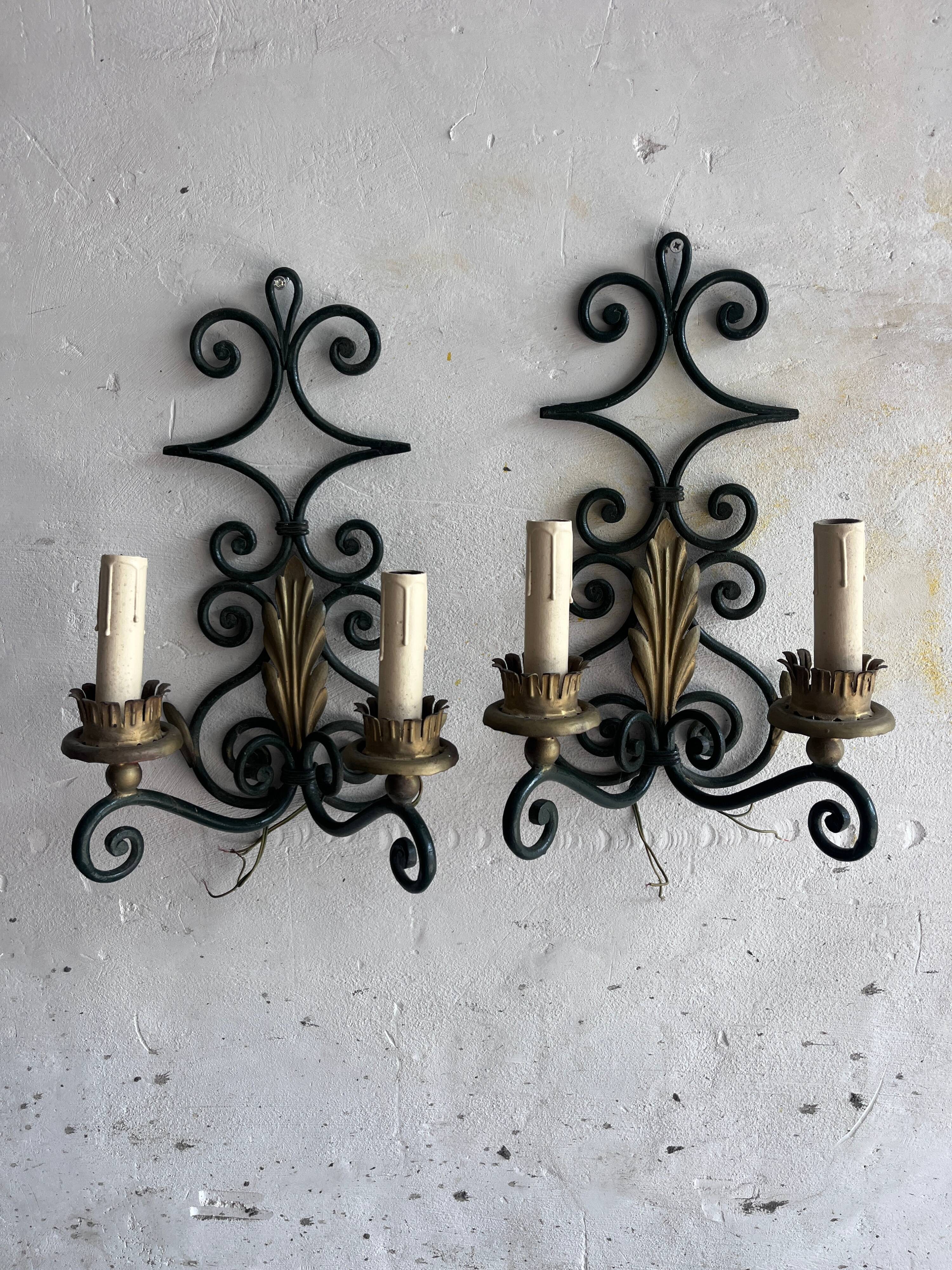 Pair of wall sconces in wrought iron with golden leaf patterns.